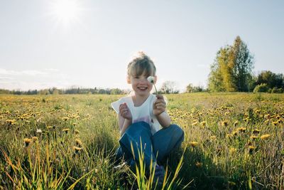Young girl happily holding a flower sat in a flower field in summer