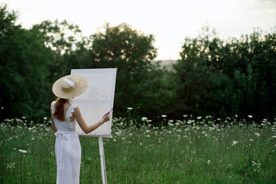 Woman wearing hat standing on field