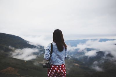 Rear view of woman standing on mountain against sky