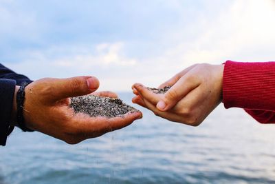 Close-up of man holding hands against sky