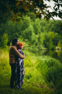 Smiling couple standing by pond over grassy land