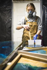 Female resin artist mixing with respirator mask