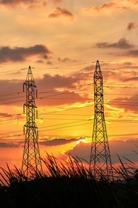 Low angle view of silhouette electricity pylon on field against romantic sky