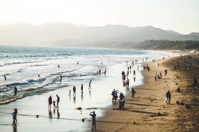 Crowd at beach against sky