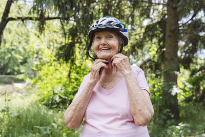 Smiling senior woman wearing cycling helmet in park