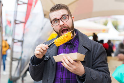 Portrait of man eating corn outdoors
