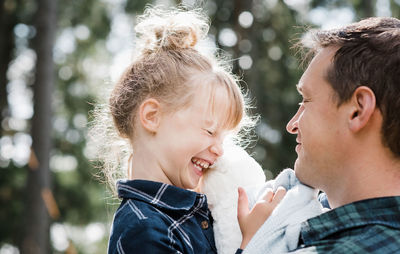 Little girl laughing with her daddy carrying her smiling at her