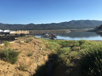 Scenic view of river and mountains against clear blue sky