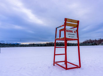 Information sign on snow covered field against sky