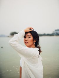 Side view of young woman standing by sea