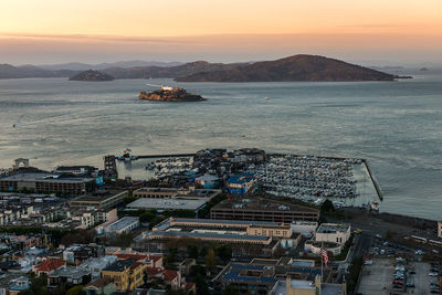 High angle view of buildings by sea against sky during sunset