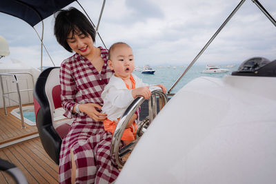 Cute boy holding steering wheel of yacht in sea