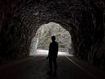 Rear view of silhouette man walking on road in tunnel