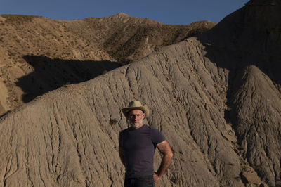 Adult man in cowboy hat on desert against mountain. almeria, spain