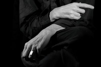 Midsection of man sitting against black background