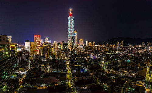 Illuminated buildings in city against sky at night