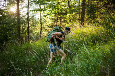 Side view of woman walking by grass in forest