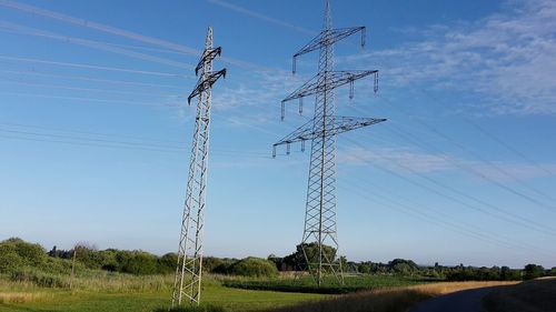 Low angle view of electricity pylon on field against sky