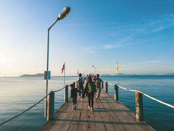 People standing on pier over sea against sky