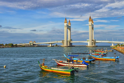 Sailboats moored on river against buildings