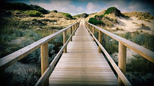 Footbridge over lake against sky