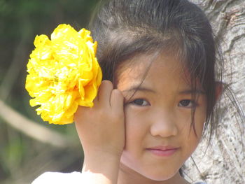 Close-up portrait of cute girl with yellow flower