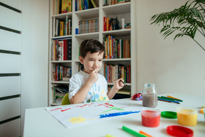Boy doing painting while sitting at home