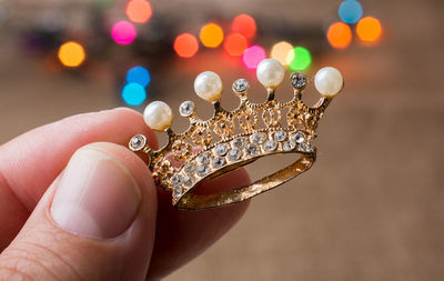 Cropped hand holding crown against defocused illuminated lights