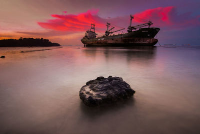 Silhouette boat in sea against sky during sunset