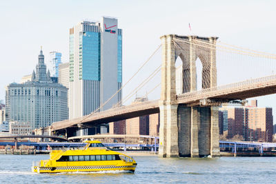 Bridge over river by buildings against sky in city