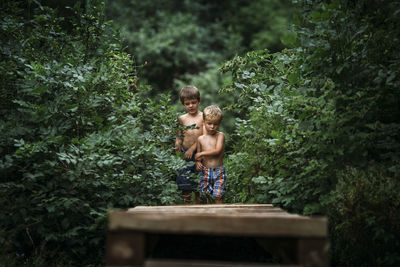 Shirtless brothers walking in forest