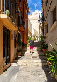 Rear view of woman walking on street amidst buildings