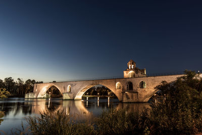 Arch bridge over river by building against sky