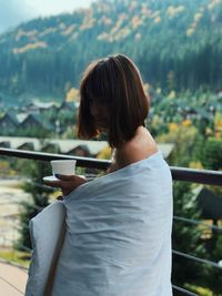 Rear view of woman standing against railing