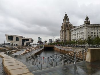 View of building by river against cloudy sky