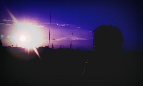 Silhouette man photographing illuminated against sky at night