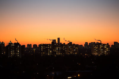 Illuminated cityscape against sky during sunset