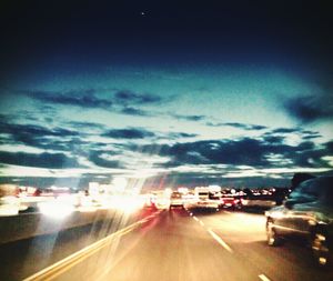 Cars on road against cloudy sky