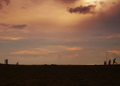 Silhouette man on landscape against sky during sunset