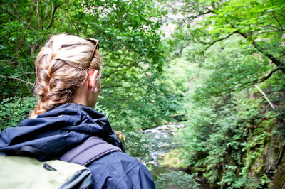 Rear view of female hiker with backpack hiking in forest