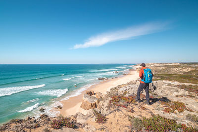 Rear view of woman walking at beach against clear blue sky