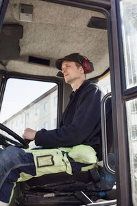 Side view of construction worker driving excavator at site