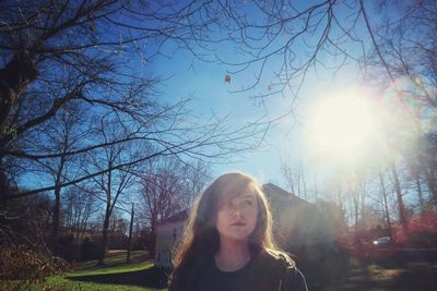 Young woman with arms raised against trees