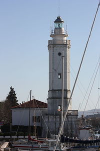 Lighthouse by sea against clear sky