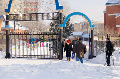 Rear view of people walking on street during winter