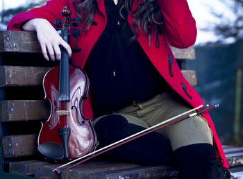 Woman sitting on bench with violin