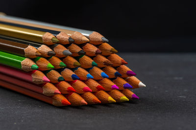 Close-up of multi colored pencils on table against black background