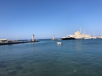 Sailboats in sea against clear blue sky