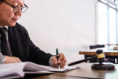 Midsection of man reading book while sitting on table