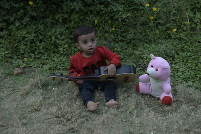 Full length of cute baby boy sitting on grass